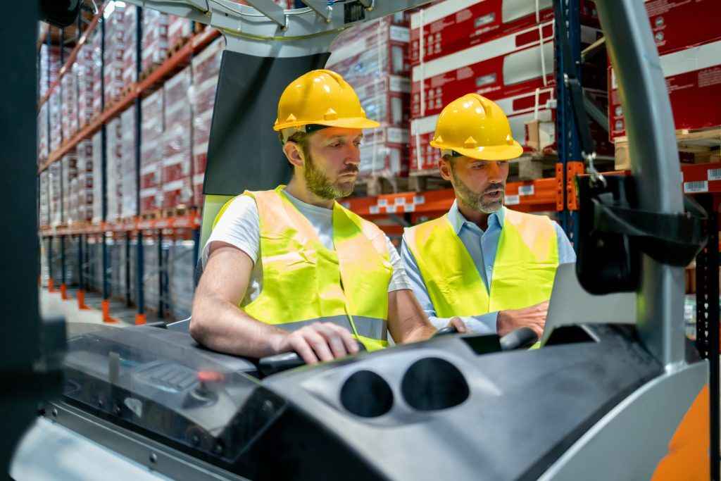 Forklift operator talking with his manager in large warehouse